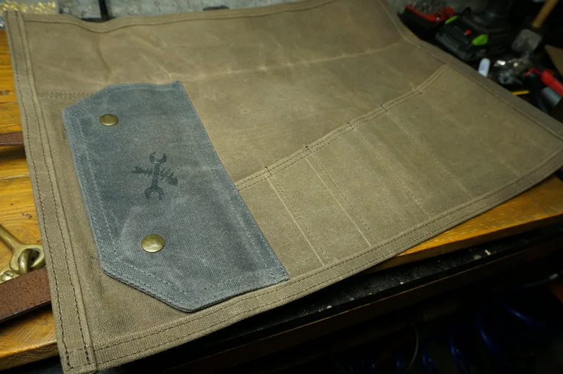 Unrolled Tool Roll „Nine Lives“ in Desert Tan with pockets and a grey flap.