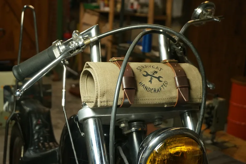 Tool Roll „Nine Lives“ in Desert Tan, strapped to a motorcycle handlebar.