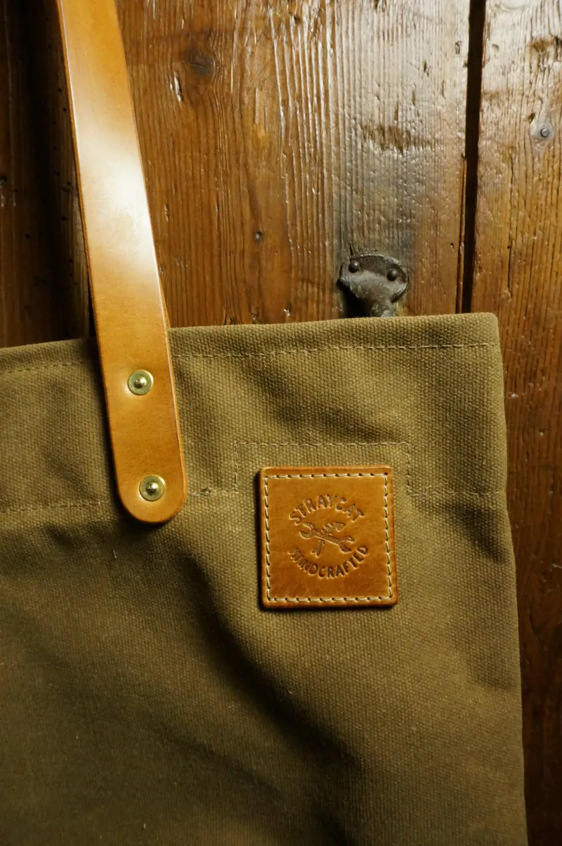 Detail: light leather handle with brass rivets and leather patch with logo.