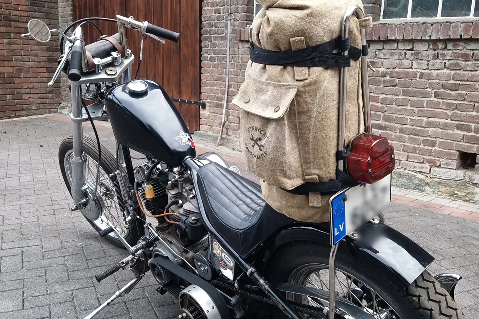 Motorcycle from behind against a brick wall, with the canvas Sissybar Bag and its screen-printed logo on the back.